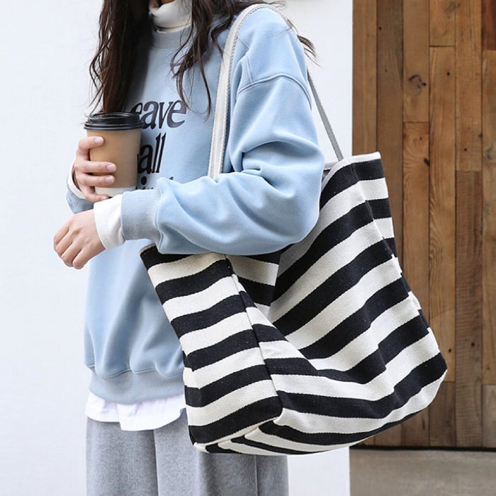 Model carrying a black striped tote bag on shoulder, easy for commuting and weekends.