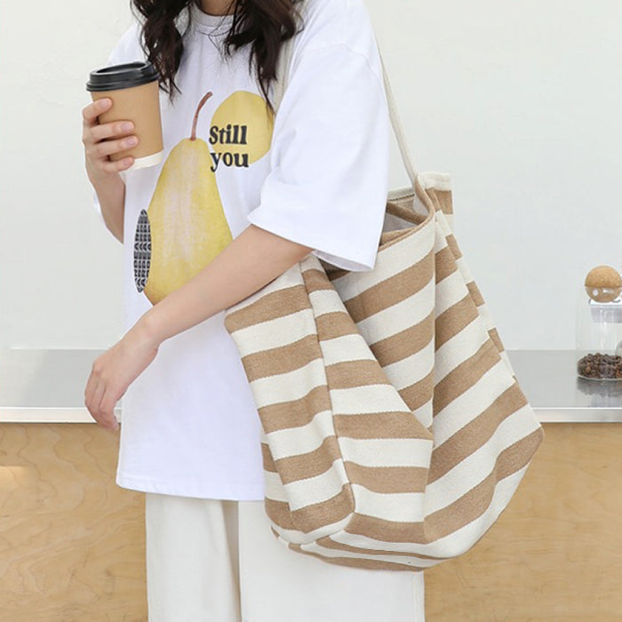Model carrying a khaki striped tote bag on shoulder, great for daily carry and travel.