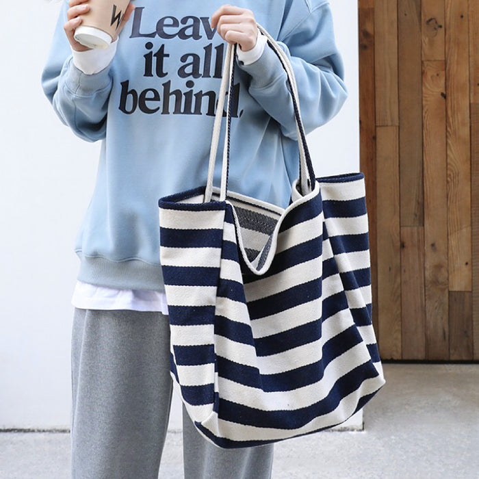 Model carrying a navy blue striped tote bag handheld, great for daily carry and travel.