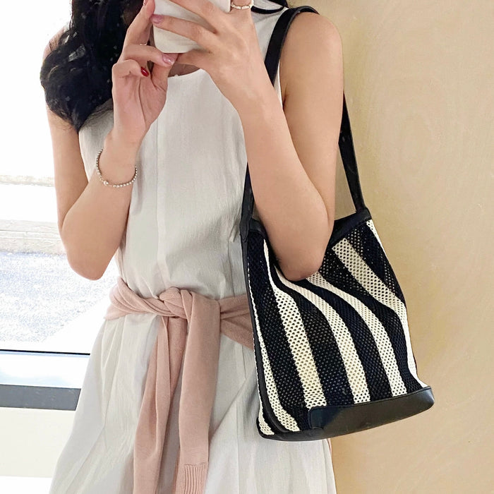 Model carrying a black striped shoulder bag on the shoulder, easy for commuting and weekends.