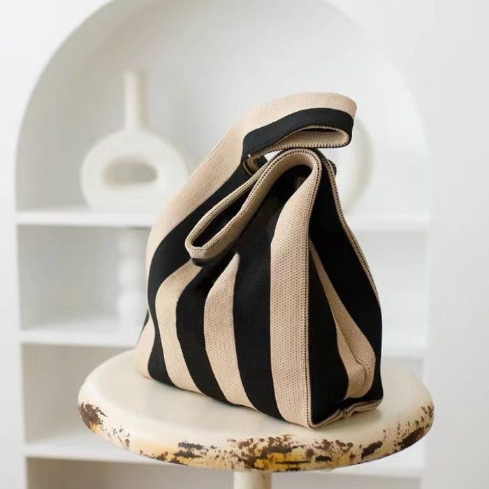 Close-up of a black and brown striped woven knitted bag, showing the tactile woven texture and integrated handle