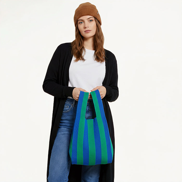 A woman holding a black and green stripe woven tote bag,  highlighting a french-style.