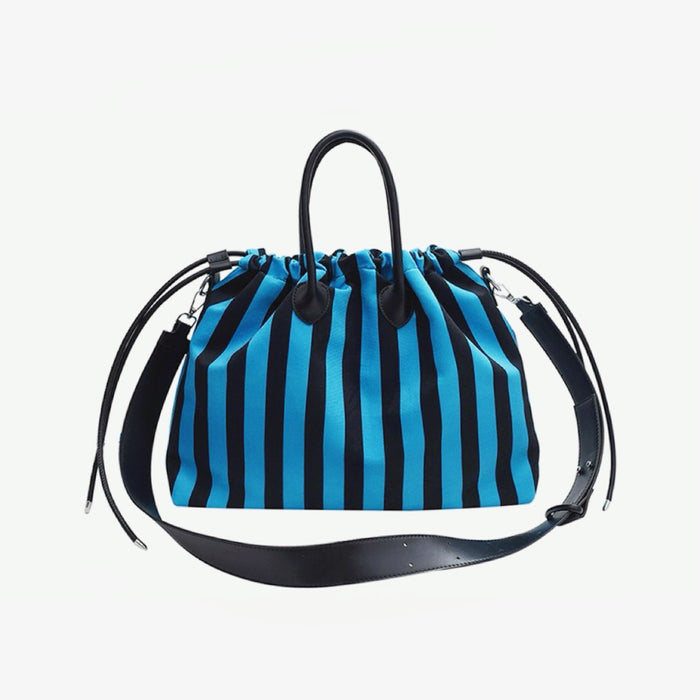 Flat lay of the blue striped drawstring bag with black PU leather handles; durable polyester material under $50.