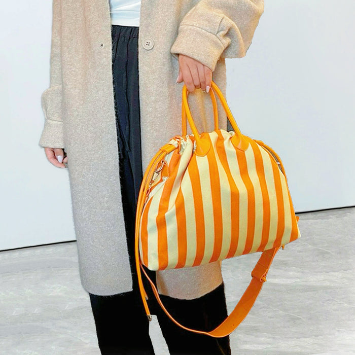 Close-up of  model holding orange striped bag by the grab handle; highlighting the drawstring closure and PU leather detail.