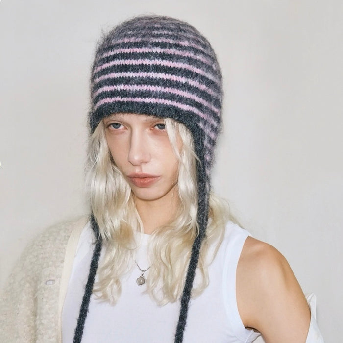 Front view of a model wearing the pink and dark grey striped earflap hat for a cozy look.