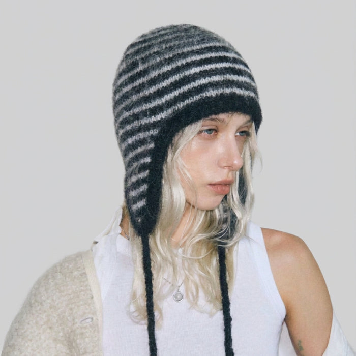 Side view of model wearing the classic black and white striped earflap hat.