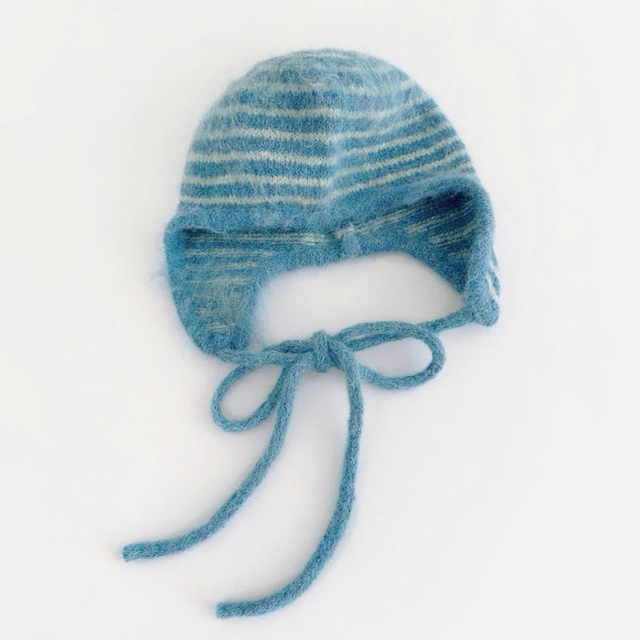 Blue and white striped knit earflap hat with braided tassel ties on white background.