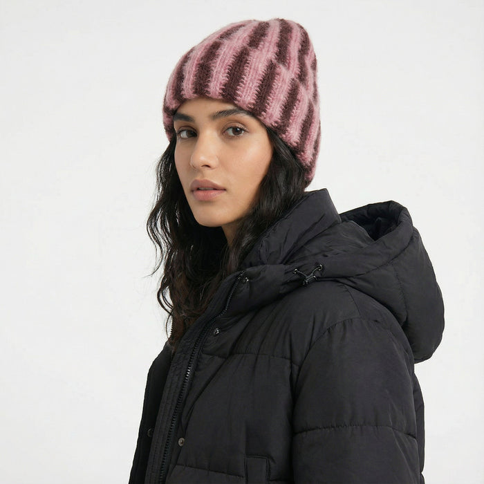 Woman wearing a coral pink and brown striped fluffy knit beanie, showcasing soft, textured insulation.