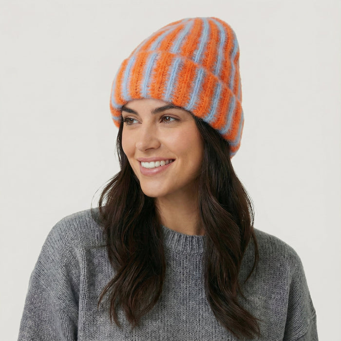 Model wearing Striped Fluffy Knit Beanie in orange blue. Vibrant striped pattern in a soft, snug fit.
