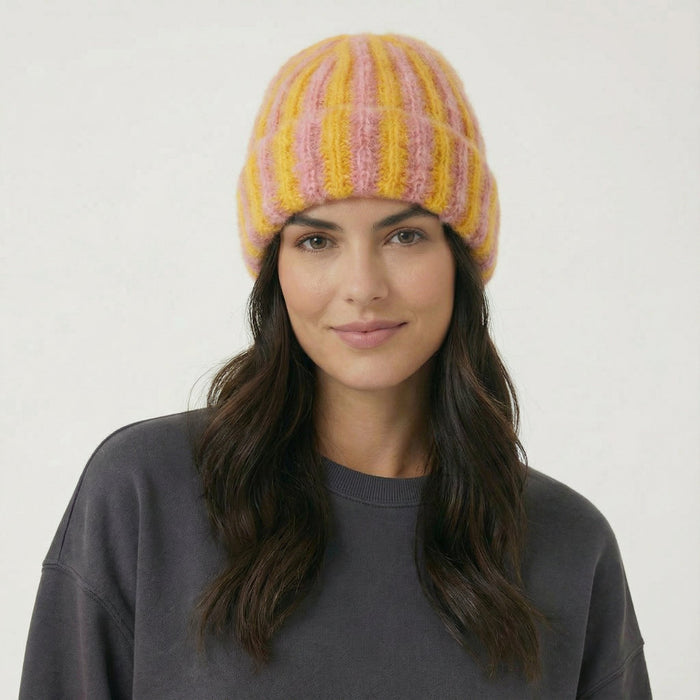 Model wearing Striped Fluffy Knit Beanie in yellow coral. Bold colorful stripes in a breathable knit finish.