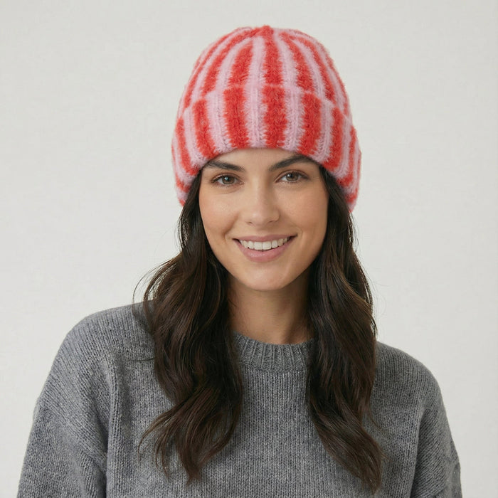 Model wearing Striped Fluffy Knit Beanie in pink. Soft, lightweight construction with a trendy striped design.