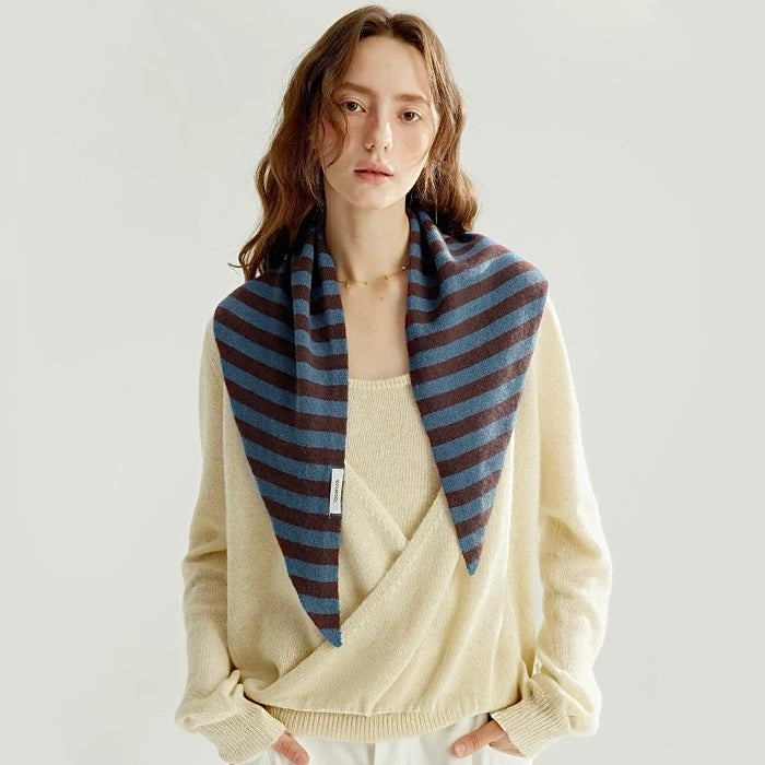 Model wearing a blue and brown triangular wool scarf drapes over shoulders, showcasing its classic striped.