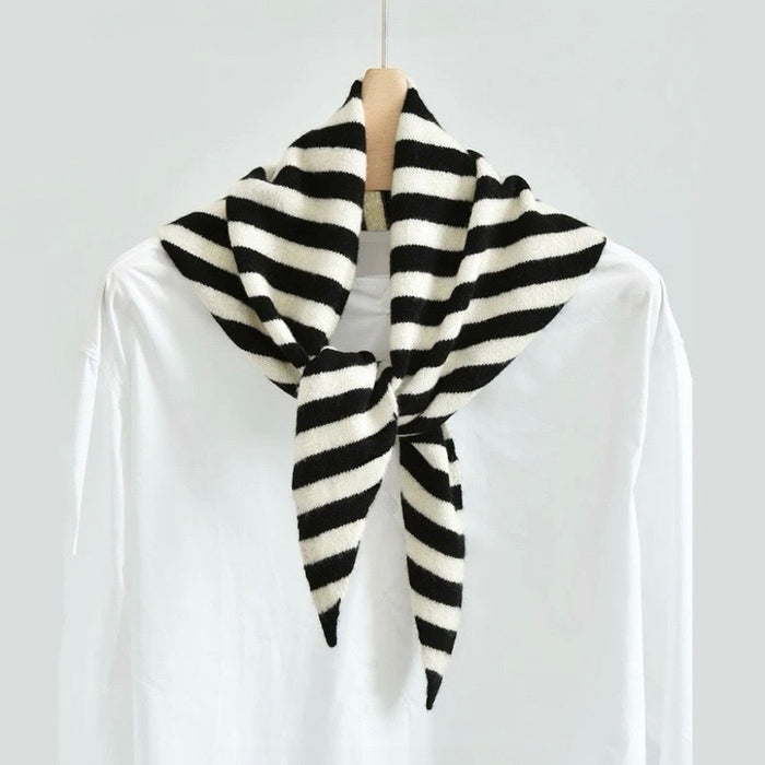 Angled view of the black and white wool striped triangle scarf on a hanger, easy for travel packing and gifting.