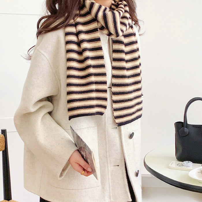 Model wearing a striped knit scarf in black and khaki, easy for weekend styling and gifting.