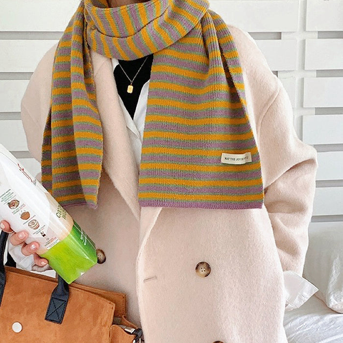 Model wearing a striped knit scarf in purple and yellow, great for office layering and commuting.
