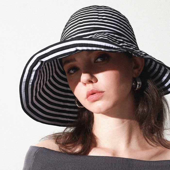 Model wearing Striped Wide Brim Bucket Hat in black. Versatile monochrome striped sunhat for travel.