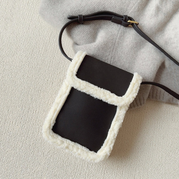 Flat lay of  Suede Crossbody Bag With Plush Trim in black, great for everyday carry and travel.