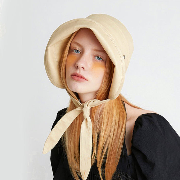 Model wearing the cream yellow ribbon bucket hat tied elegantly in a bow.