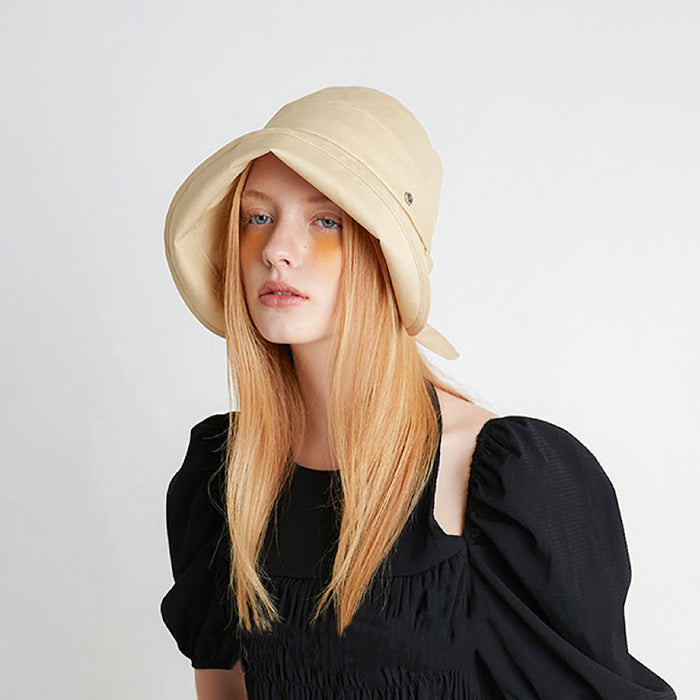 Fashion shot of the cream yellow sun shield hat paired with a black summer dress.