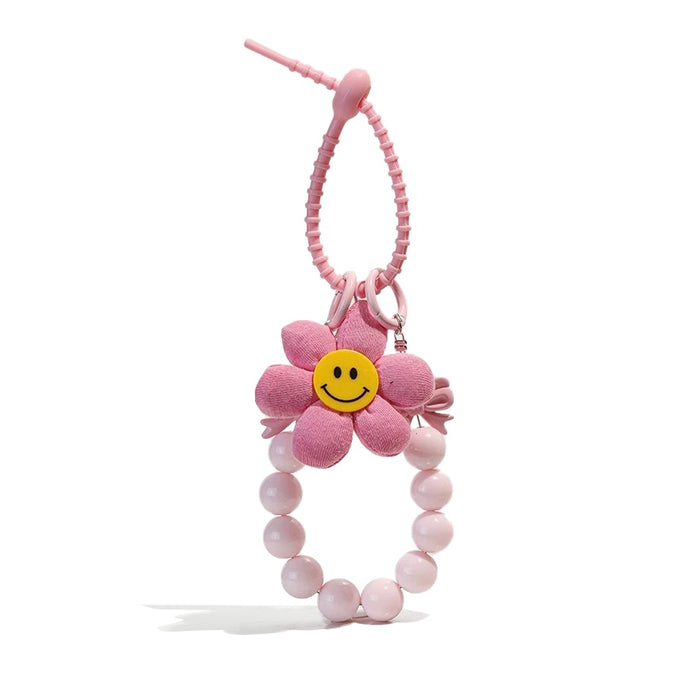 Front view of Pink flower bag charm with a yellow smiley face, beaded wristlet, and removable elements.