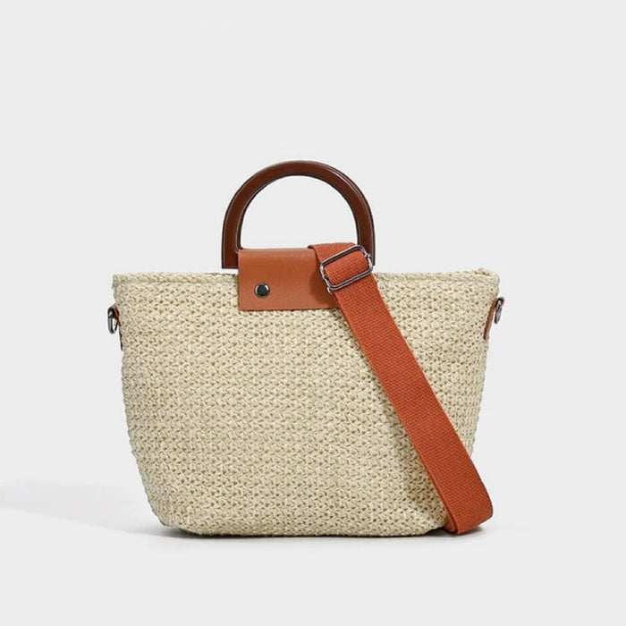 Angled view of Beige raffia straw woven bag with brown wooden handles, tan leather accents, and an orange adjustable strape.