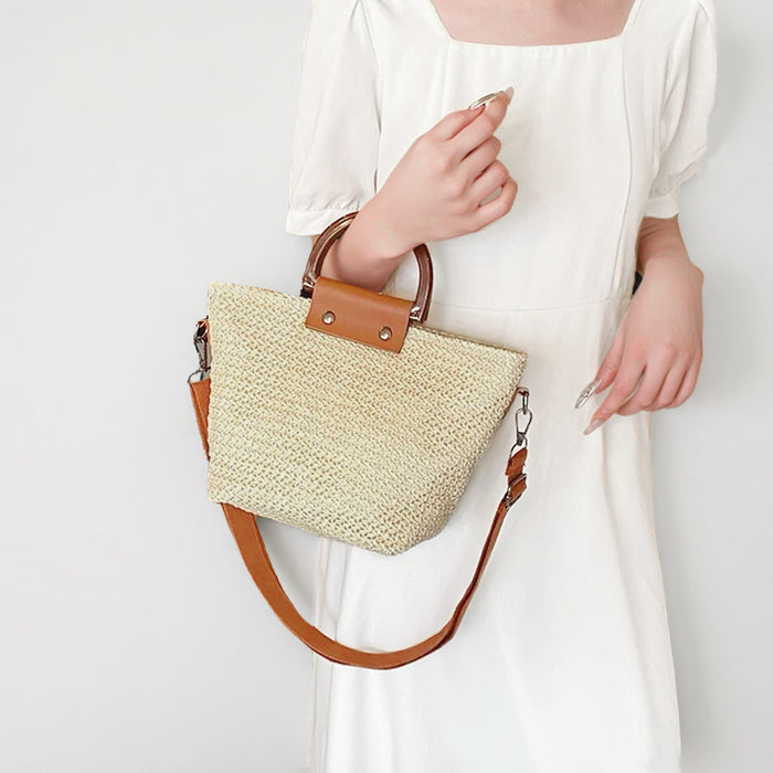Model carrying the light beige raffia straw woven bag with brown grab handles.