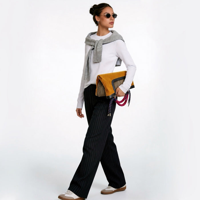 Model in black and white casual outfit, holding the tote bag as foldable clutch, full-body shot.
