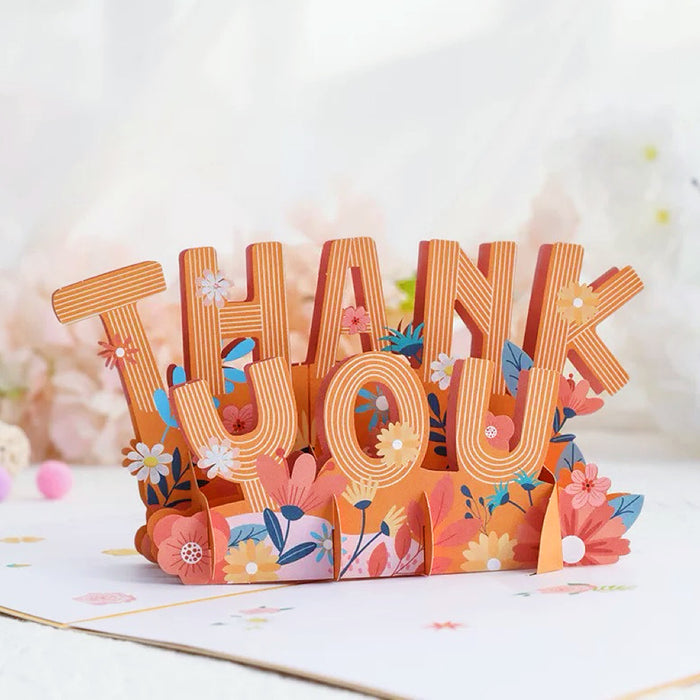 Close-up of  greeting card with colorful floral design and 3D Thank You Text.