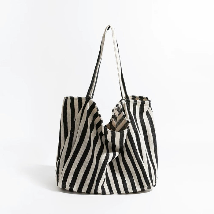 Black and white thin stripe canvas tote bag with shoulder strap and open top.
