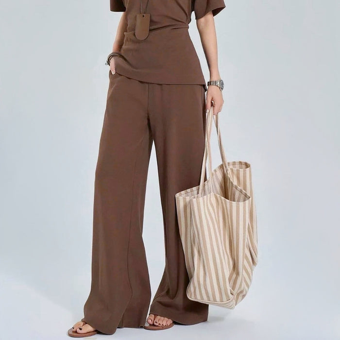 Model carrying khaki striped tote by hand; spacious design perfect for travel essentials and gym gear.