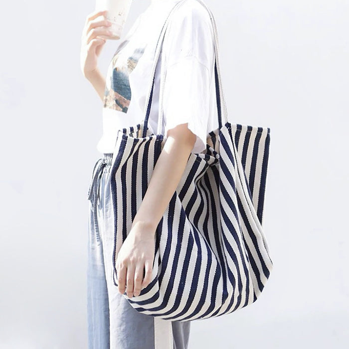Model styling navy blue striped tote over shoulder, durable canvas fabric ideal for students and campus life.