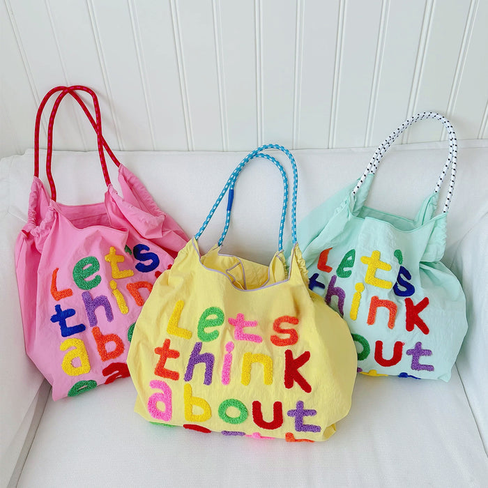 Front view of Three cotton tote bags in pink, yellow, and mint green with colorful embroidered.