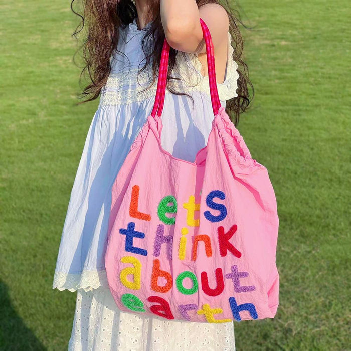 Model carrying a pink Think About Earth Tote Bag on the shoulder , great for everyday carry and travel.