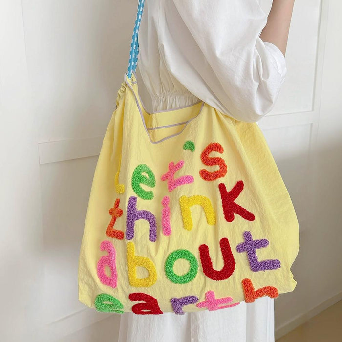 Model carrying a yellow Think About Earth Tote Bag on her shoulder, easy for commuting and weekends.