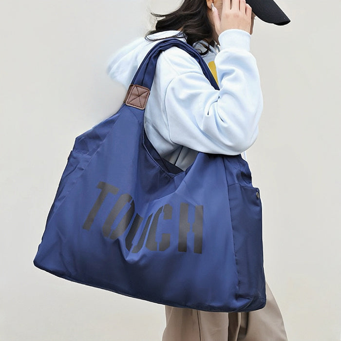 Model carrying a  Touch Nylon Weekend Bag  in blue, easy for commuting and weekends.