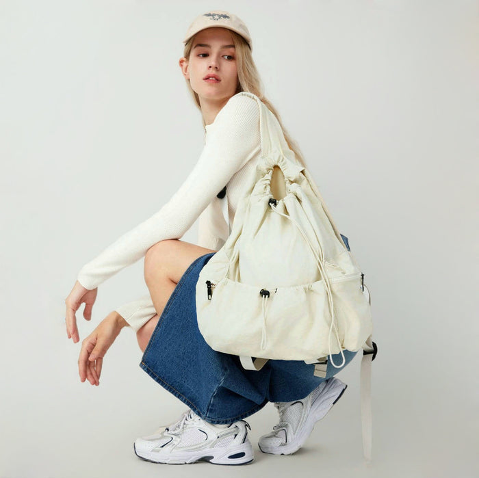 Model wearing white drawstring backpack; spacious design ideal for carrying books and laptops on campus.