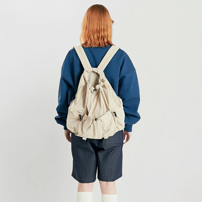 Model wearing white backpack while crouching; durable polyester fabric perfect for rugged weekend adventures.