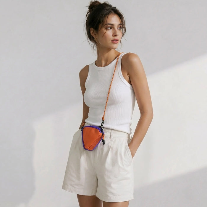 Model wearing a white tank top and shorts showcasing an orange triangle nylon pouch worn as a crossbody bag.