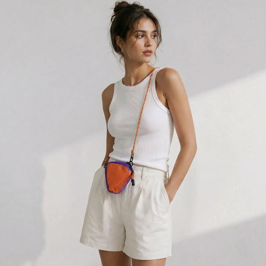 Model wearing a white tank top and shorts showcasing an orange triangle nylon pouch worn as a crossbody bag.