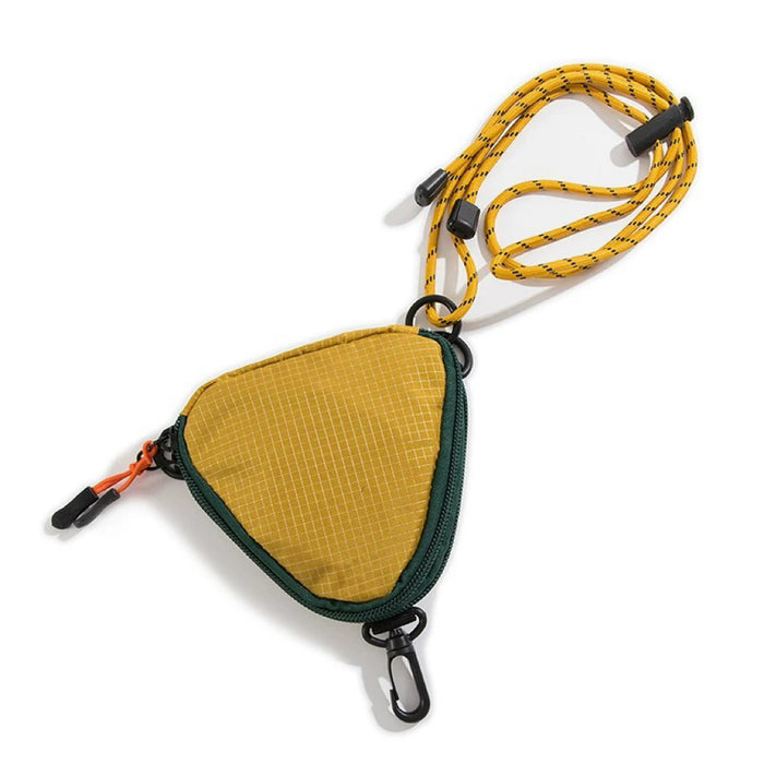 Studio flat lay of the yellow and black triangle nylon pouch showing the zip-top fastening and the attached patterned paracord strap.
