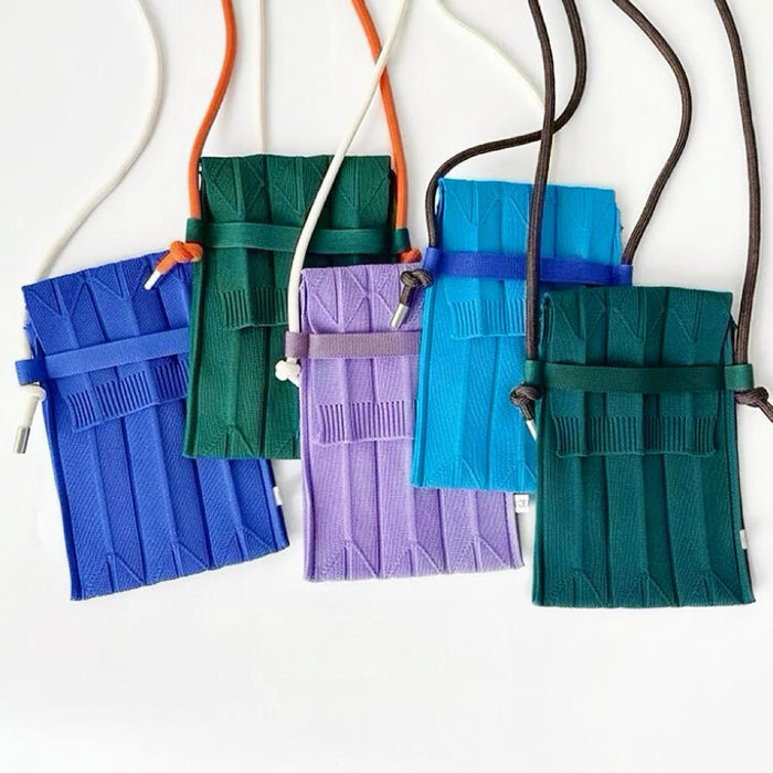 Angled view of Five Vivid Knit Pleat Mini Bags in blue, green, purple, light blue, and dark green with adjustable strap.