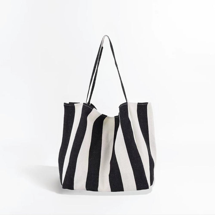Angled view of Black and white wide stripe canvas tote bag with shoulder straps and an open top.