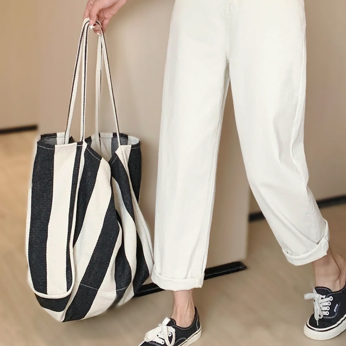 Model carrying a black and white Wide Stripe Canvas Tote Bag handheld, ideal for errands and gifting.