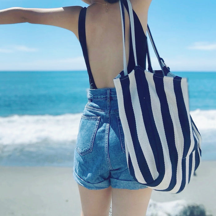 Model carrying a blue striped tote bag on the shoulder, ideal for city walks and gifting.