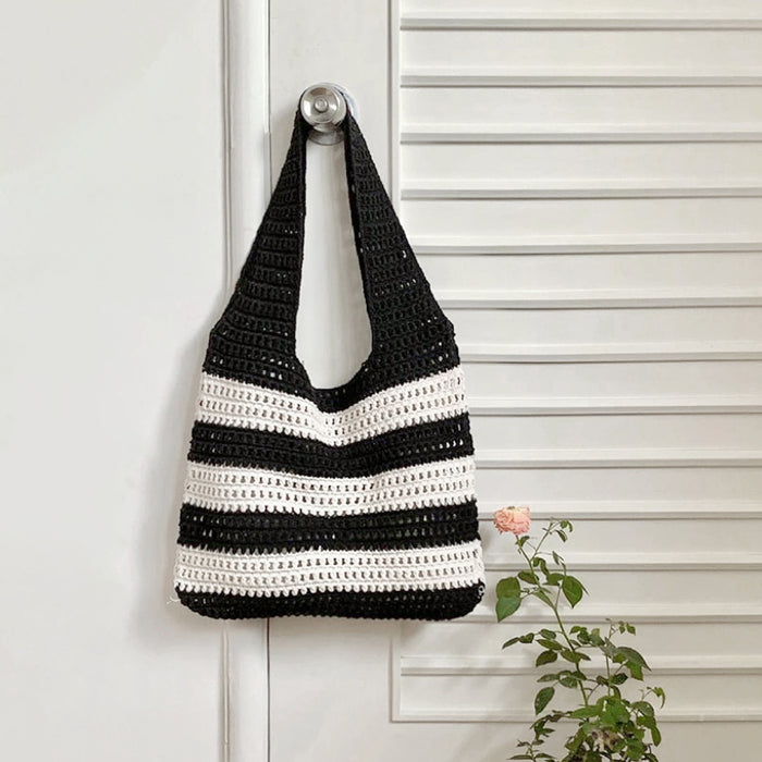 A black and white Wide Stripe Crochet Bag hanging on a door, easy for commuting and weekends.