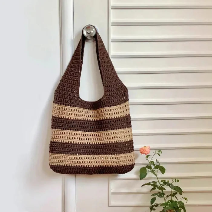 Flat lay of Wide Stripe Crochet Bag in brown hanging on a door, great for everyday carry and travel.
