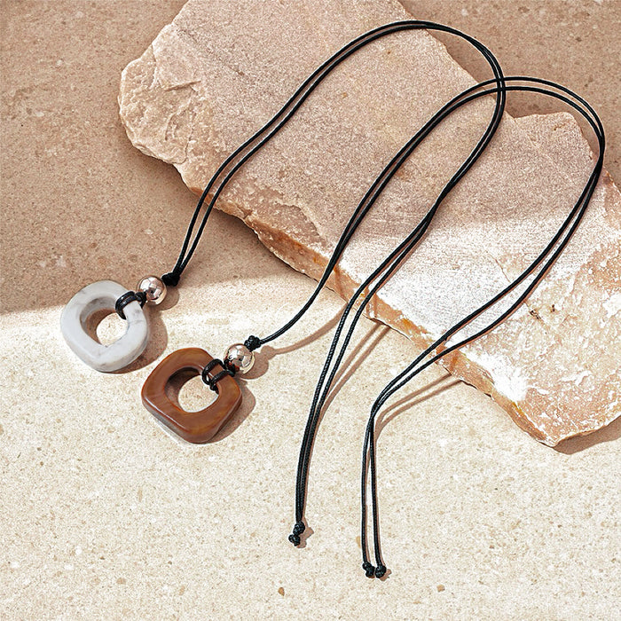 Front view of two pieces of Wild Grace Geometric Pendant Necklace in brown and grey.