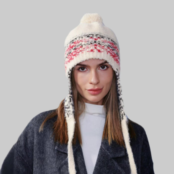 Model wearing beige Winter Isle Ear Flap Hat, displaying traditional Fair Isle patterns in a thick warm knit.