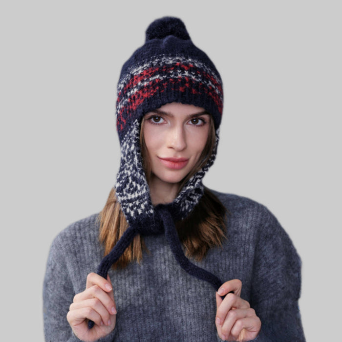 Model wearing navy blue Winter Isle Ear Flap Hat, features classic Nordic motifs in a durable thermal knit.
