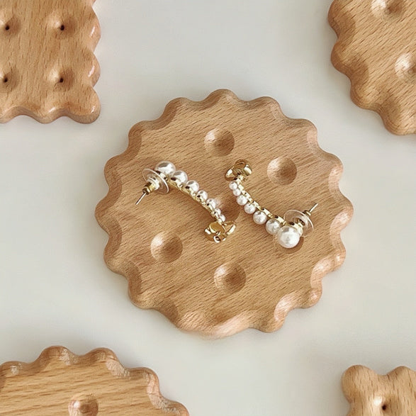 Flat lay of round Wooden Biscuit Coaster with earrings on it , great for home decor and organization.